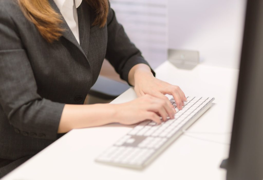 オフィスでデスクトップPCのキーボードを打つ女性